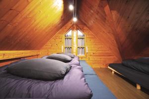 a bedroom with four pillows in a wooden cabin at The Creek Cottage in Habu