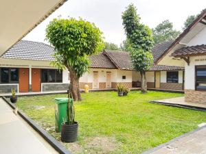 a yard of a house with two trees and a trash can at Roemah Kavaleri powered by Cocotel in Bandung