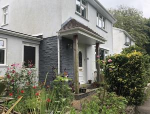 a white house with a white door and some flowers at Stylish Room Close to Beaches in Falmouth