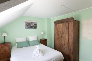 une chambre avec un lit blanc et une armoire en bois dans l'établissement Ker Aventin - Jolie maison classée 3 étoiles, à Pléneuf-Val-André