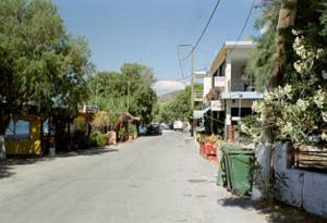 an empty street in a town with buildings and trees at Xenos Apartments in Keratokampos