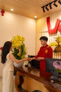 un homme et une femme debout à un comptoir dans l'établissement Vooc Signature Hotel Hoi An, à Hội An