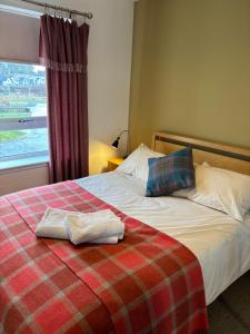 a bed with a plaid blanket and a window at Gorgeous Dornoch apartment in Dornoch