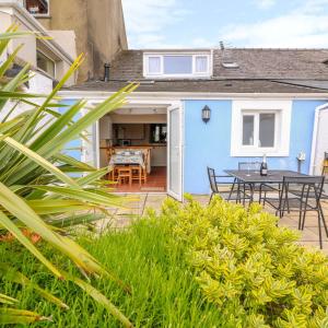 a blue house with a patio and a table at Characterful and quirky cottage in beautiful Pembs in Fishguard