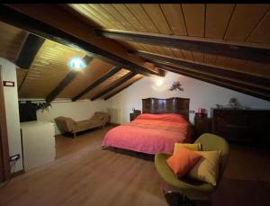 a bedroom with a bed and a couch in a attic at Casa montagna relax in Cedegolo