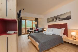 Habitación de hotel con cama y sala de estar. en Hotel Dolomitenhof & Chalet Alte Post en Sesto