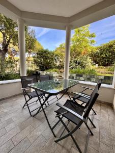 a glass table and two chairs on a patio at Verdeacqua my villa in the pinewood in Spotorno