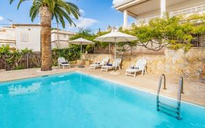 a swimming pool with chairs and umbrellas next to a house at Casita Dragonera Sant Elm by Mallorca Infinity in Sant Elm