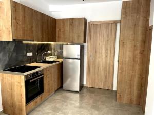 a kitchen with a white refrigerator and wooden cabinets at Margie Town, Studio Αpartment in Zakynthos