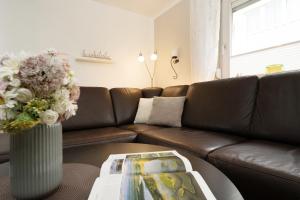 un salon avec un canapé en cuir marron et un vase avec des fleurs dans l'établissement Ferienhaus Freitag, à Kellenhusen 42 autres photos