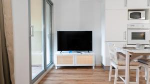 a living room with a television on a white cabinet at Le Corsaire - Séjour Relaxant, Plage & Piscine in Carqueiranne