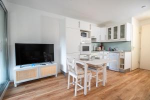 a white kitchen with a table and a tv at Le Corsaire - Séjour Relaxant, Plage & Piscine in Carqueiranne