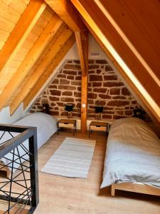 a attic bedroom with two beds and a stone wall at Grange Des Rêves in Lichtenberg