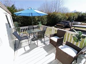 a patio with a table and chairs and an umbrella at Charming Caravan To Hire At Breydon Water Holiday Park In Norfolk Ref 10003Tc in Belton