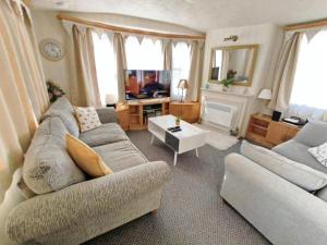 a living room with a couch and a table at Charming Caravan To Hire At Breydon Water Holiday Park In Norfolk Ref 10003Tc in Belton
