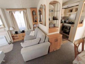 a living room with a couch and a kitchen at Charming Caravan To Hire At Breydon Water Holiday Park In Norfolk Ref 10003Tc in Belton