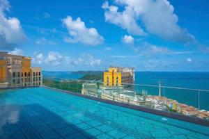 a swimming pool on the roof of a building with the ocean at SenSea Hillside Apartment - Sunset Town in Phu Quoc