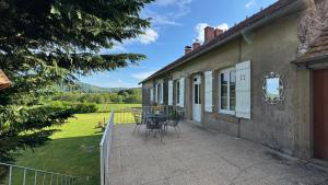 Un patio de una casa con una mesa y sillas. en Maison Belle Vie, en Saint-Symphorien-de-Marmagne