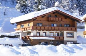 um edifício coberto de neve com carros estacionados na frente em Haus Viehhauser em Kleinarl