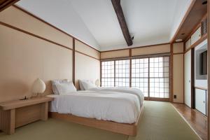 een slaapkamer met een groot wit bed en ramen bij YADORU KYOTO HANARE Tsukikage No Yado in Kyoto +13 foto's