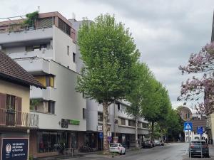 a tall white building on a city street with trees at Mini Sun in Dornbirn