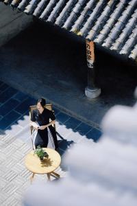 uma mulher sentada numa cadeira ao lado de uma mesa em 墨弦苑智能轻奢民宿 喜洲镇海舌公园店 em Dali