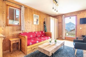 ein Wohnzimmer mit einem roten Sofa und einem Tisch in der Unterkunft NOEMA - vue montagne in La Toussuire
