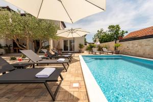 a pool with chaise lounge chairs and an umbrella at Villa La Aurora ZadarVillas in Murvica