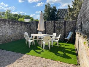 une table, des chaises et un parasol sur une pelouse dans l'établissement Maison de bourg, à Suèvres