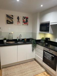 eine Küche mit weißen Schränken und einer schwarzen Arbeitsplatte in der Unterkunft New 1 Bed Apartment 12 mins to Central London and Gatwick Airport in Croydon
