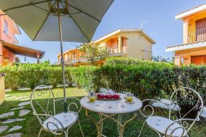 una mesa y sillas con sombrilla y fruta. en Villa Emerald private compound swimming pool, en SantʼAnna Arresi