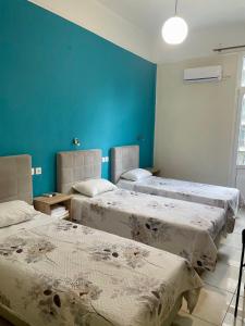 two beds in a room with blue walls at Hotel Kastoria in Thessaloniki