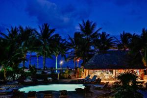 a resort with a pool and palm trees at night at Caribbean Villas Hotel in San Pedro