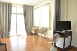 a living room with a television and a table with chairs at Velkommen Guesthouse Phnom Penh in Phnom Penh