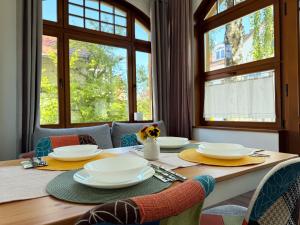 a dining room table with plates and chairs and windows at Apartamenty Żeromskiego 8 in Ustka