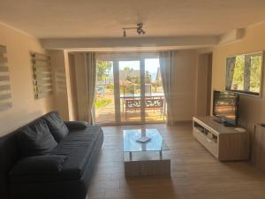 a living room with a black couch and a television at Fewo Eckernförde mit Meerblick in Eckernförde