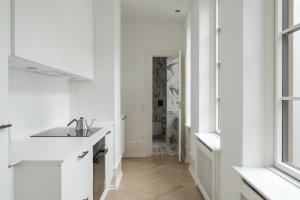 a white kitchen with a sink and a hallway at Latin Quarter by Daniel&Jacob's in Copenhagen