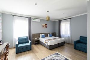 a bedroom with a bed and two blue chairs at Khan Hotel Samarkand- UNESCO World Heritage Site in Samarkand +23 photos