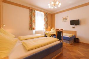 a hotel room with two beds and a tv at Hotel Tautermann in Innsbruck