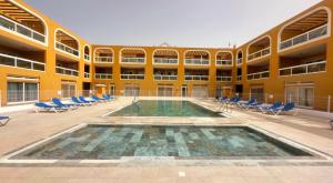 a large building with a swimming pool and chairs at Residencial Cotillo Playa in Cotillo