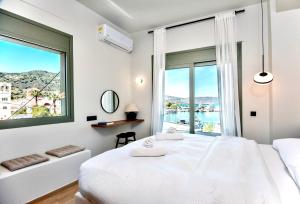 a white bedroom with a large window and a bed at Elounda Mimal Luxury Suite in Elounda
