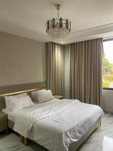 a bedroom with a large white bed with a chandelier at Executive One bed - East legon in Accra +26 photos
