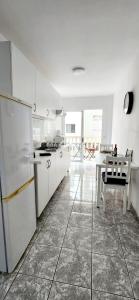a white kitchen with a table and a refrigerator at Fantastic Holiday Apartment in Arona +9 photos