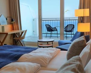 um quarto com uma cama e uma varanda com cadeiras em SeeHuus Lifestyle Hotel em Timmendorfer Strand