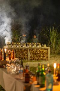 two men standing around a table with a fire grill at Sanctuary Chitwan National Park in Chitwan