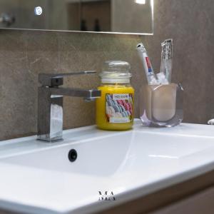 a bathroom sink with a jar of honey and a mirror at MEA Suite in Palermo