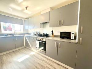 a kitchen with white cabinets and a microwave oven at Earl House in Coxhoe