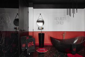 La salle de bains est pourvue d'une baignoire noire et d'un mur rouge. dans l'établissement L'Amour Suite - romantic getaway, à Tivat