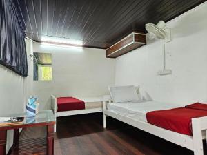 a bedroom with two beds and a desk and a table at Bamboo leaf Homestay in Meppādi