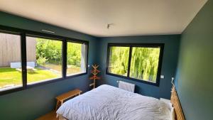 ヴール・レ・ローズにあるConfort détente près de la plageの青い壁とベッドと2つの窓がある寝室